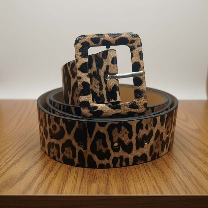 Leopard print belt with a matching buckle on a wooden surface