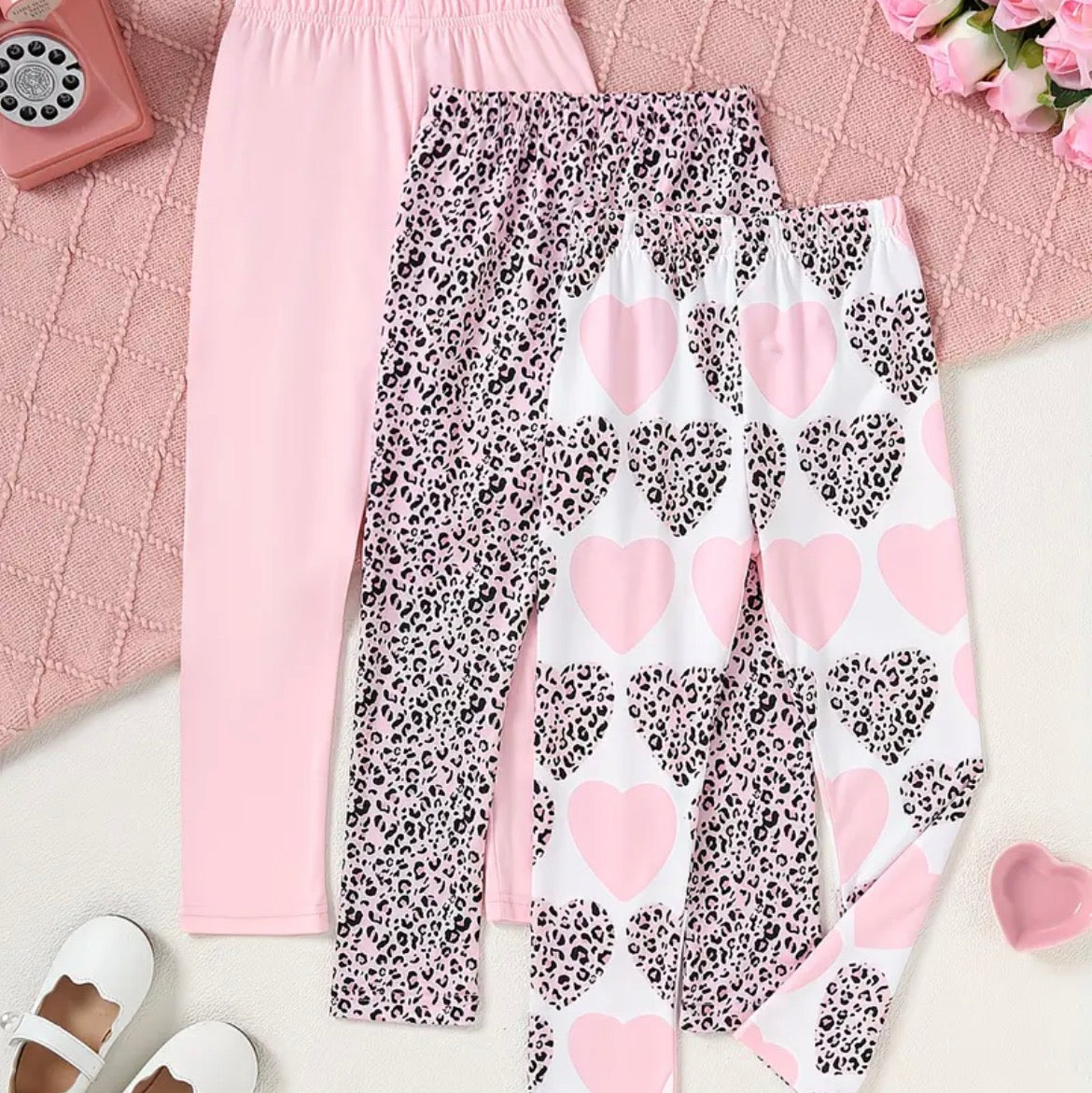 Two pairs of leggings with different patterns on a pink textured surface.