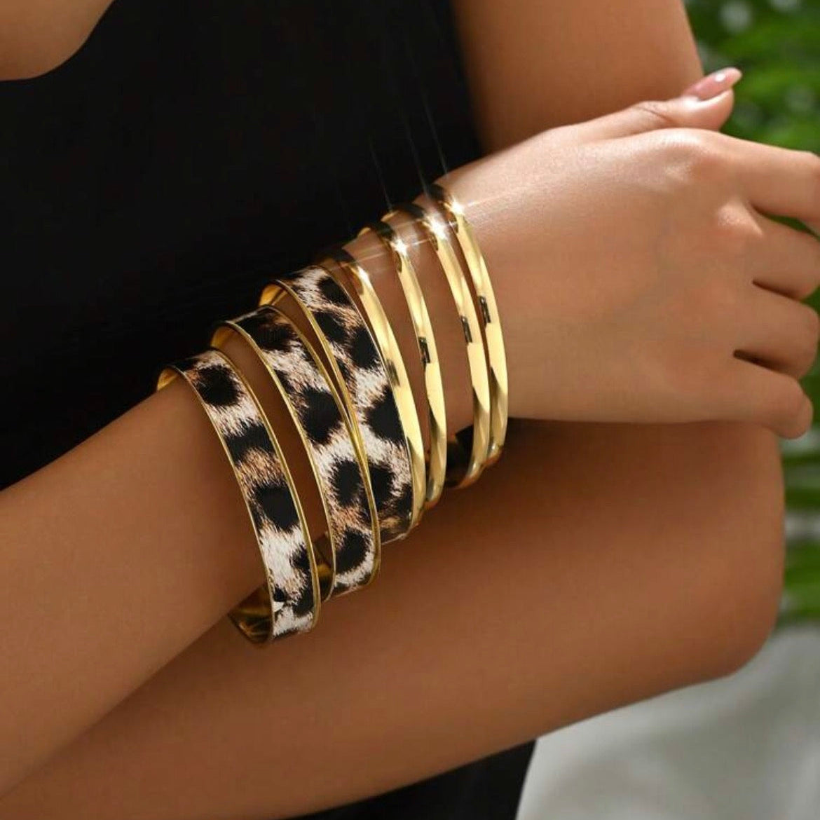 Leopard print and gold bangles on a wrist with a blurred background