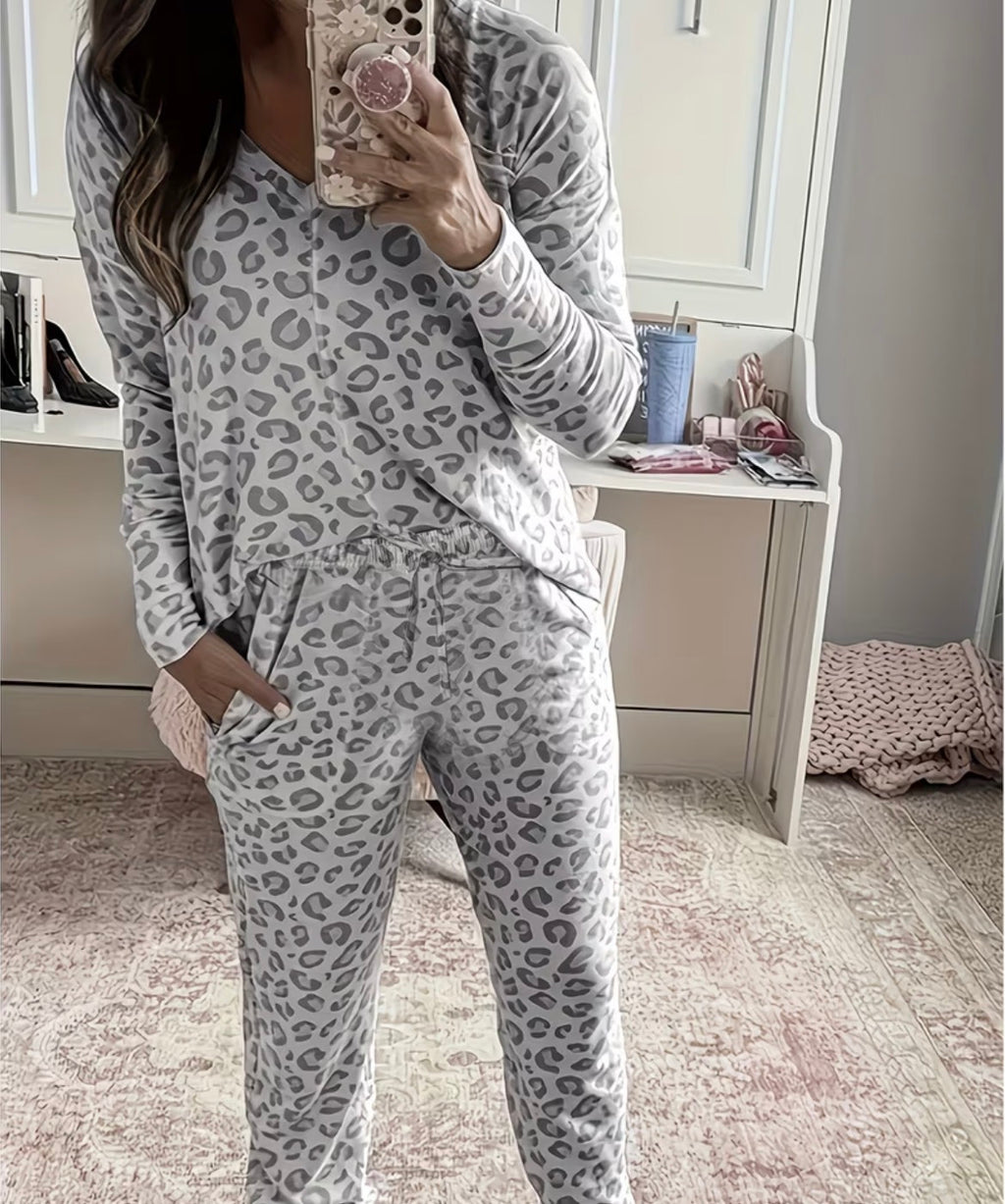Person wearing a gray leopard print pajama set in a bedroom.