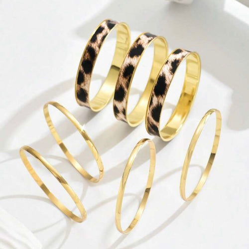 Gold bangles with leopard print pattern on a white surface