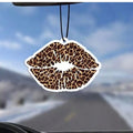 Car air freshener with leopard print lips hanging from a car's rearview mirror.