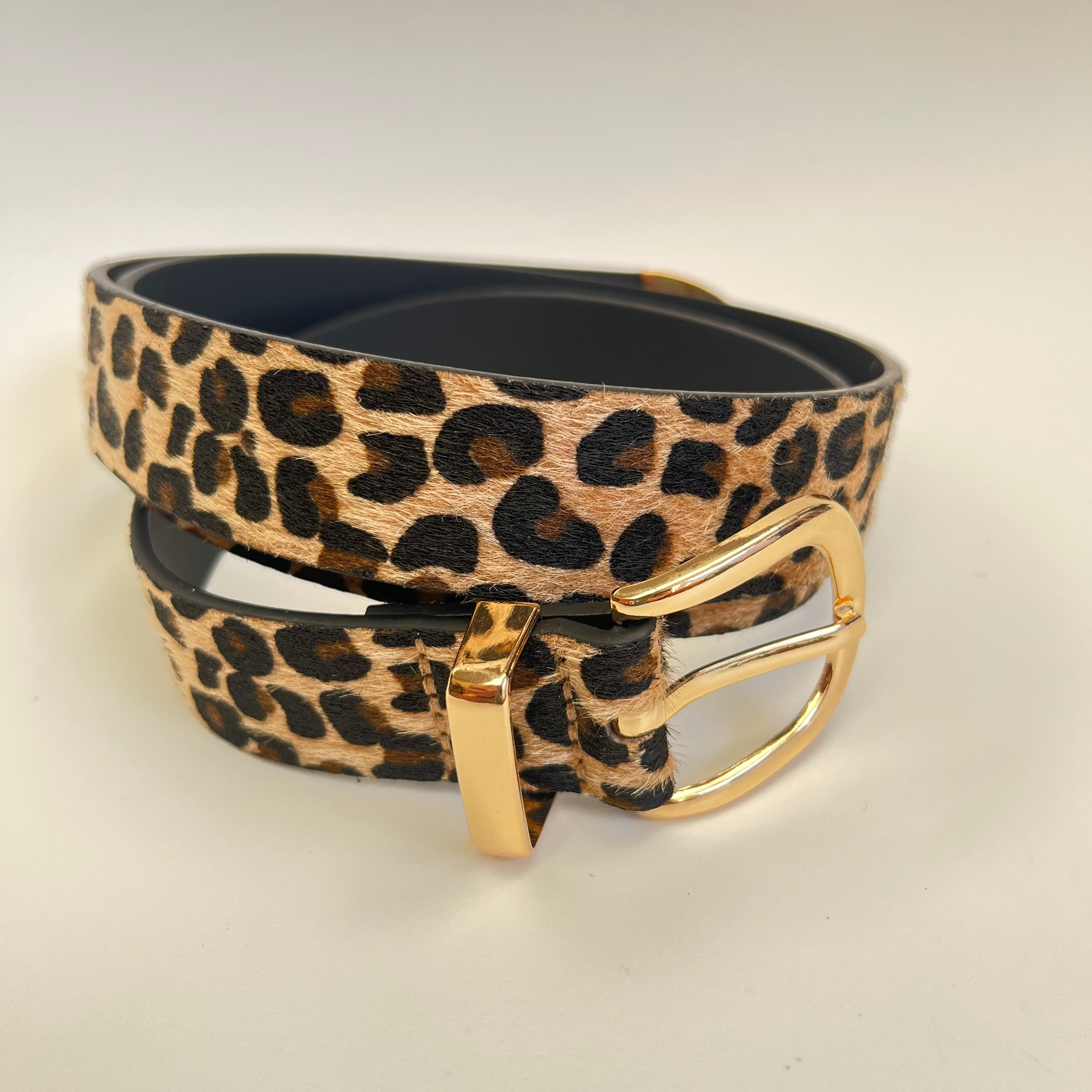 Leopard print belt with a gold buckle on a light gray background