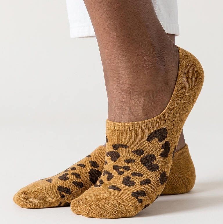 Brown leopard print socks worn with white pants on a light background