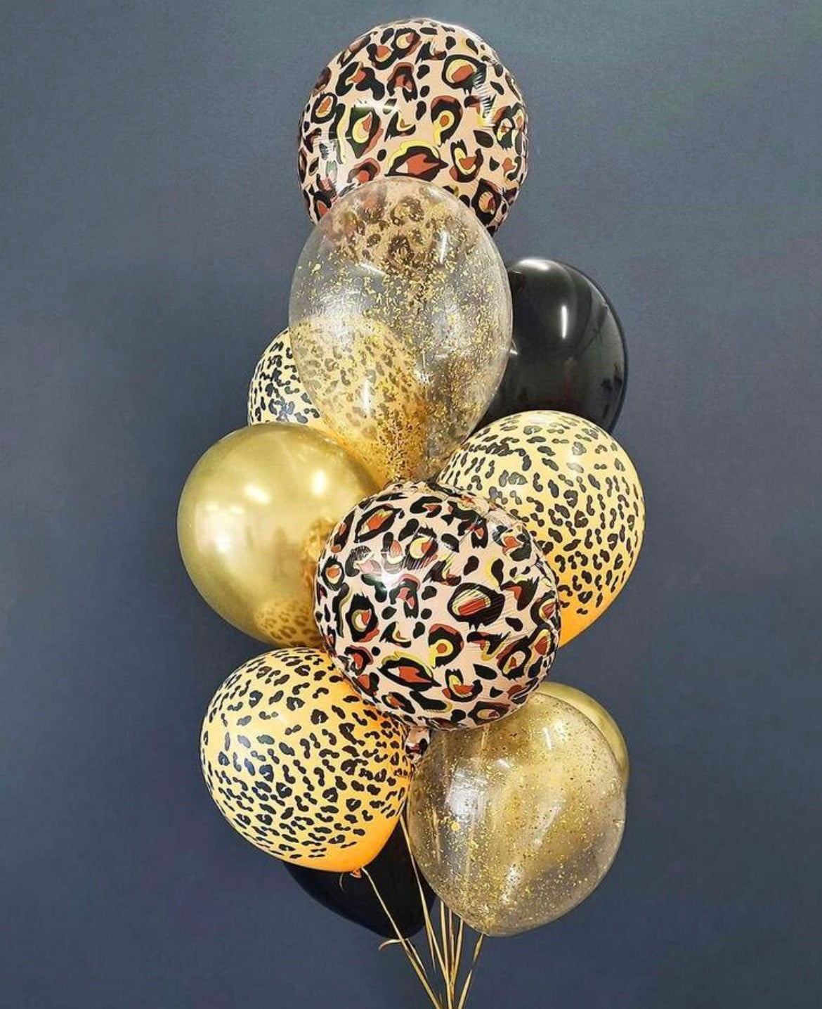 Bouquet of balloons with leopard print and gold colors against a dark background