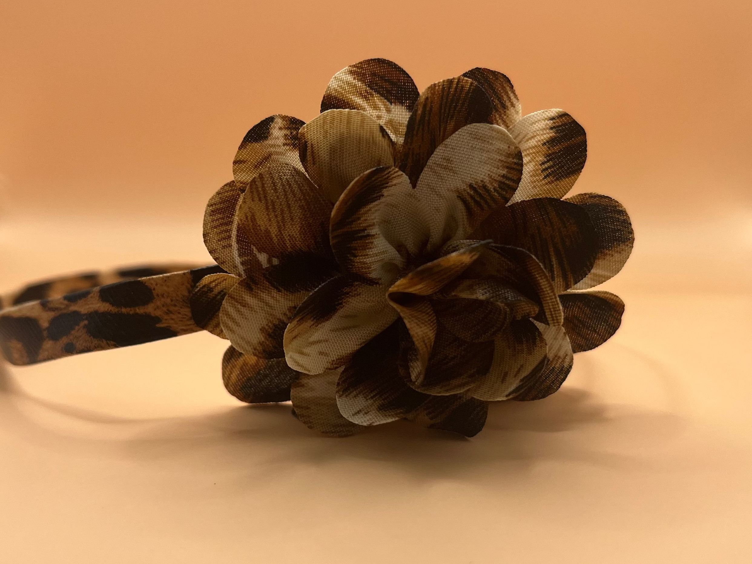 Leopard print chocker with feathered flower on a beige background