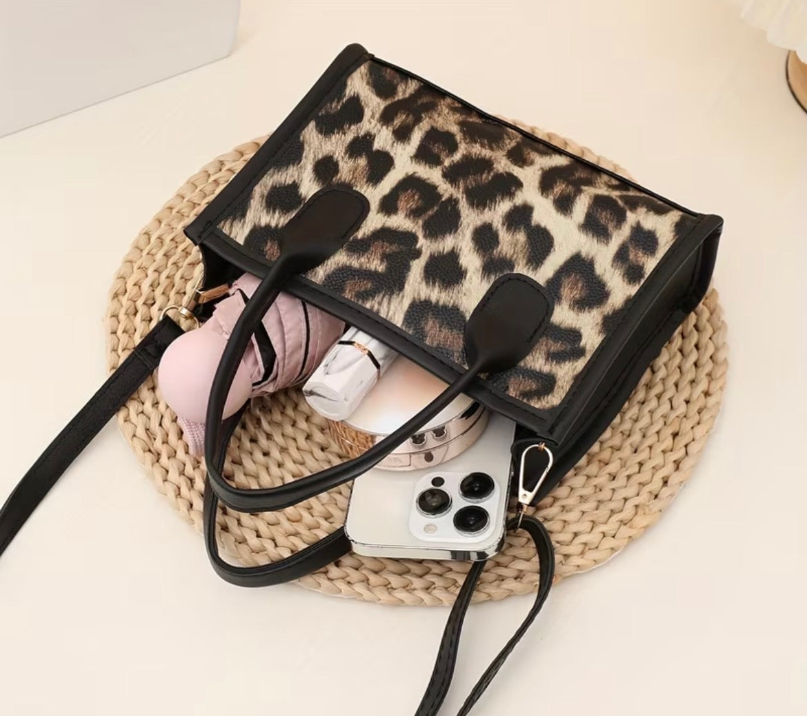 Leopard print handbag with pink shoes and a phone on a woven mat
