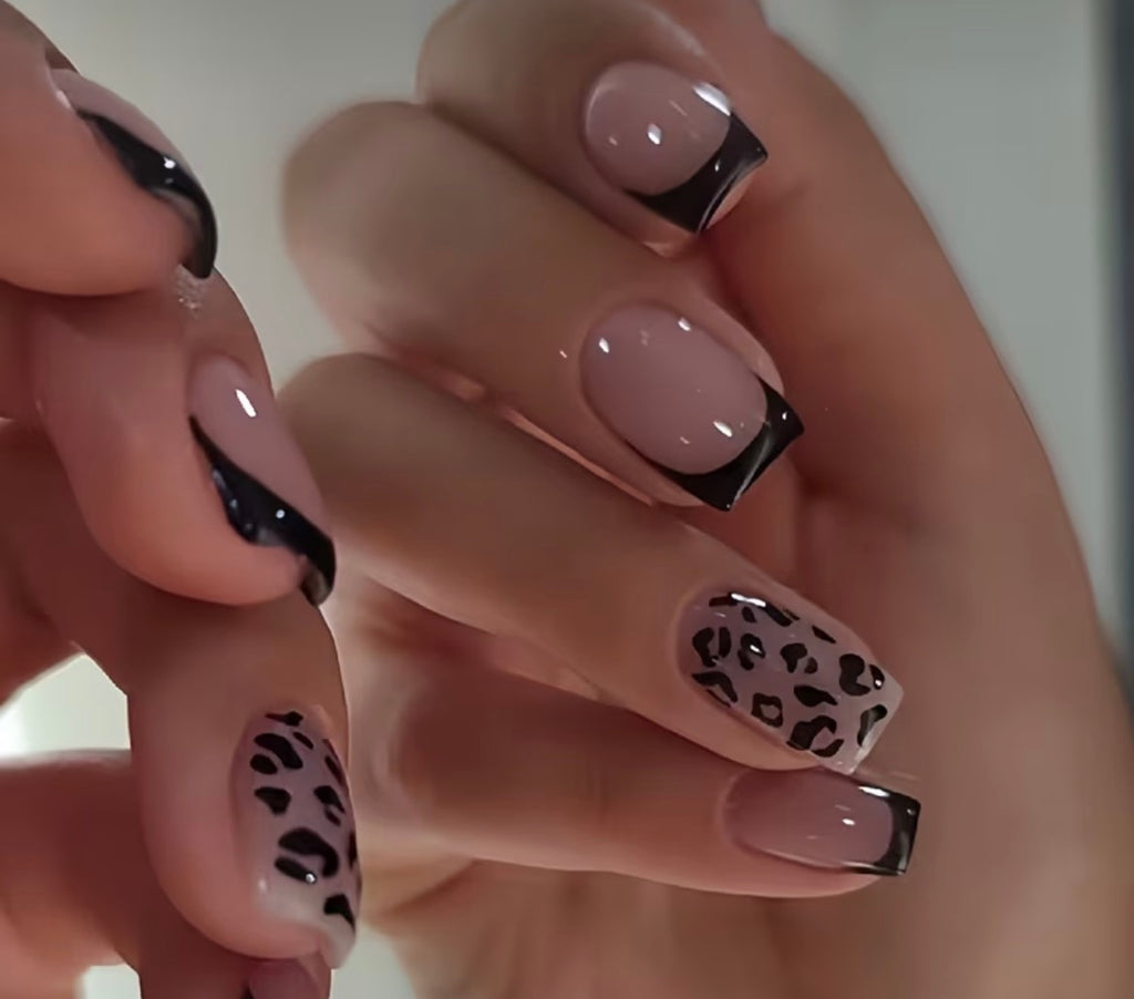Close-up of hands with pink and black nail design featuring leopard print pattern.