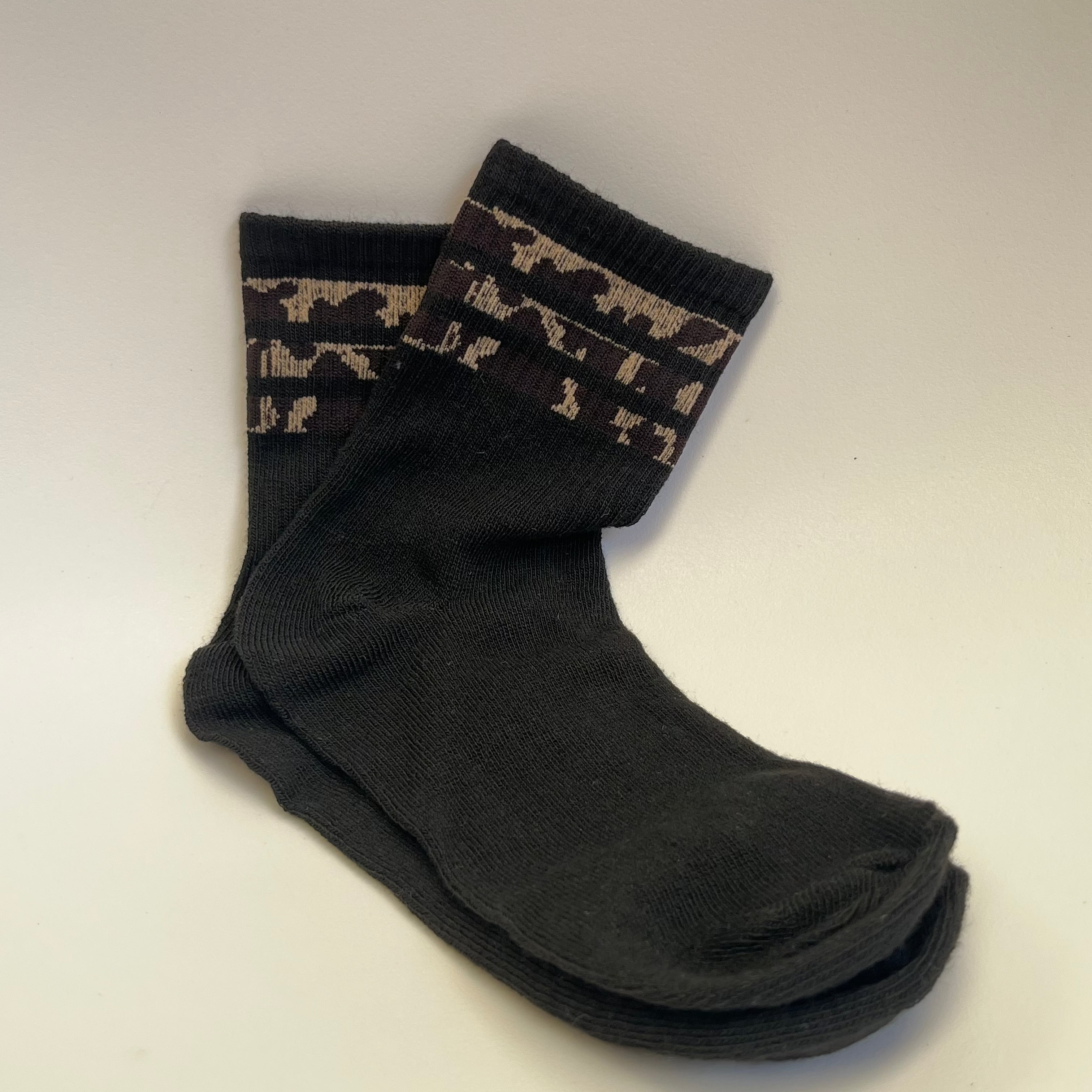 Black socks with patterned cuffs on a light gray background