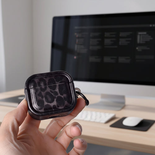 Hand holding a black leopard print case against a light gray background