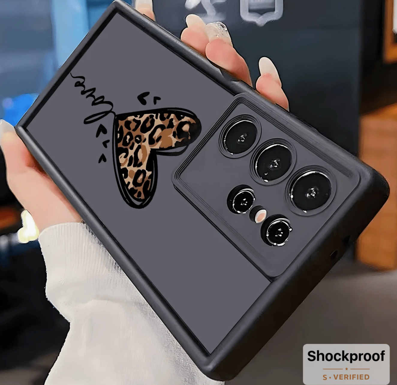 Phone case with leopard print heart design held by a person