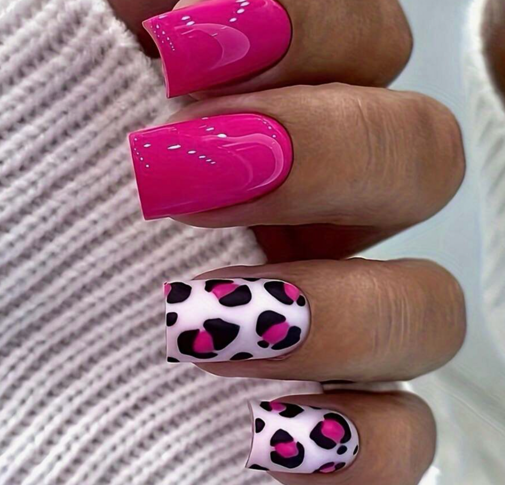 Close-up of hands with pink and leopard print nail designs on a textured surface.