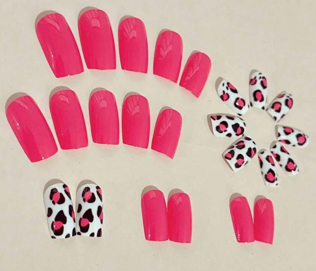 Set of pink nail extensions with leopard print tips on a beige background