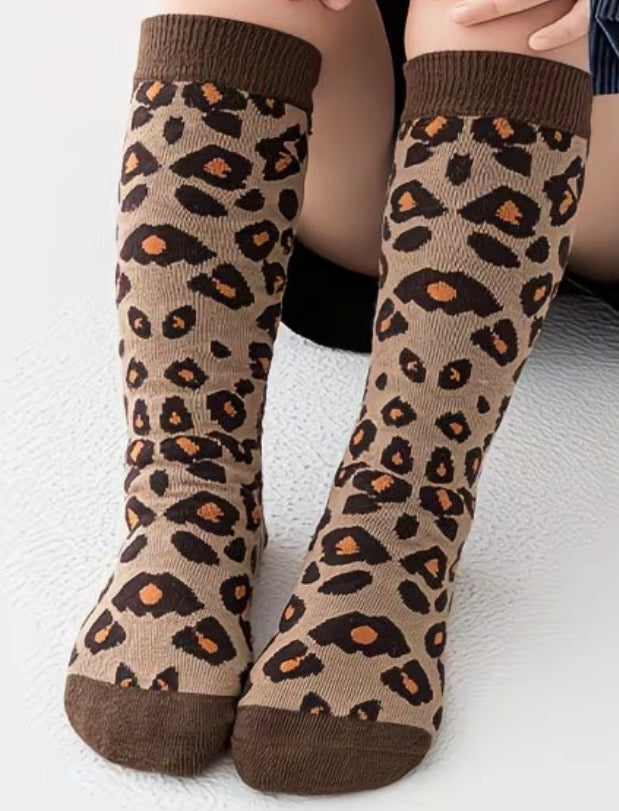 Leopard print socks worn by a child on a white background