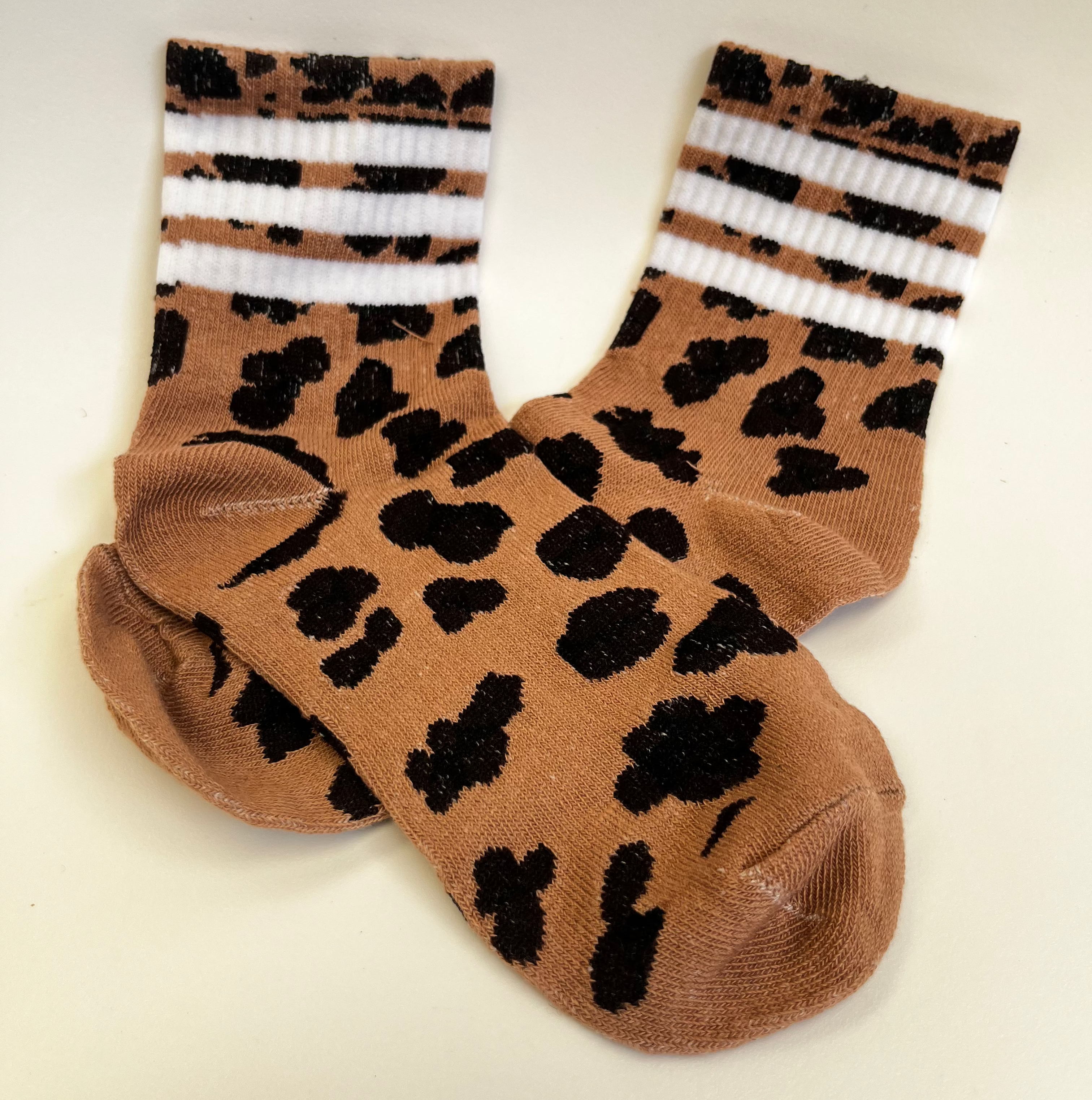 Leopard print socks with white stripes on a light gray background