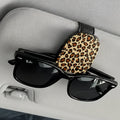 Sunglasses with a leopard print case on a car's visor.