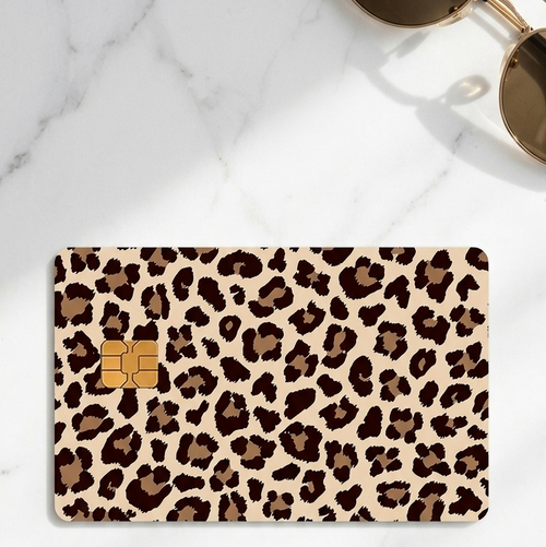 Leopard print card decal on a marble surface with sunglasses and a wallet.