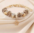 Gold bracelet with leopard print and heart charms on a beige fabric background