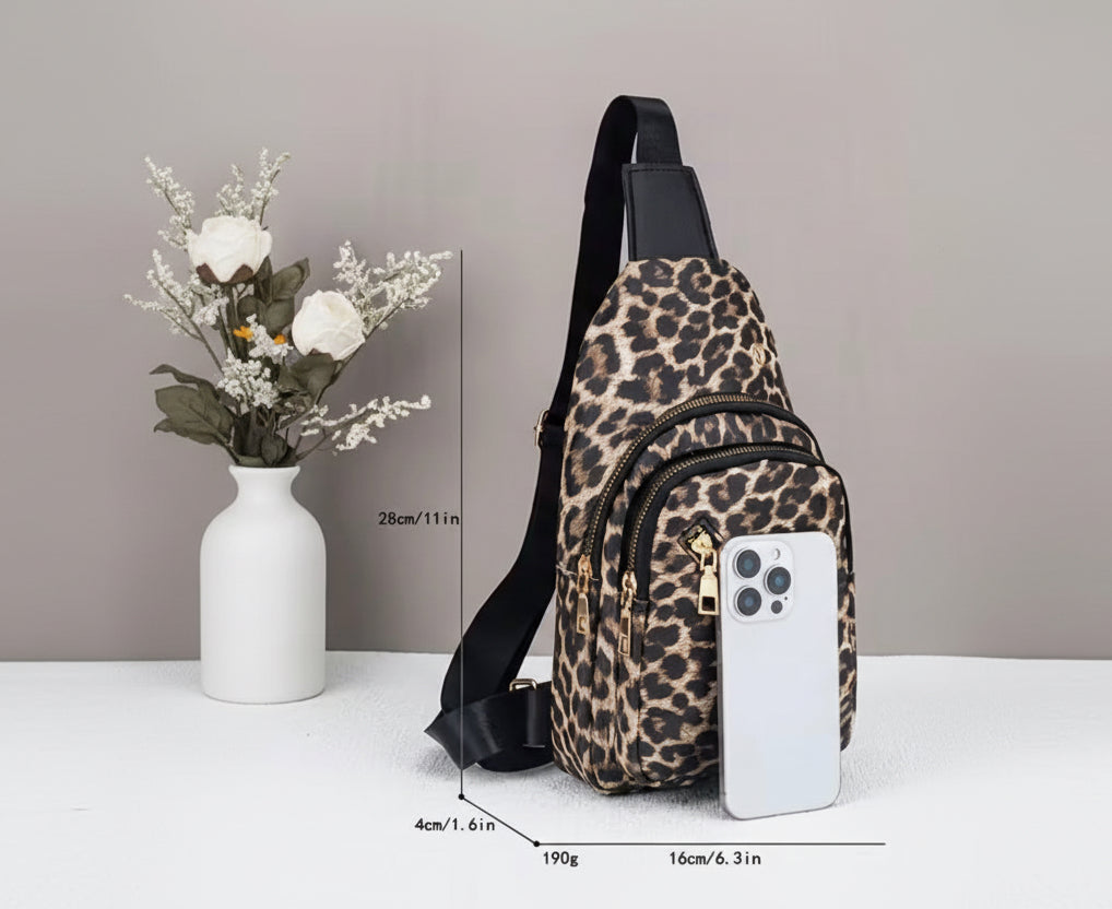 Leopard print crossbody bag with a phone on a white surface, next to floral decorations.