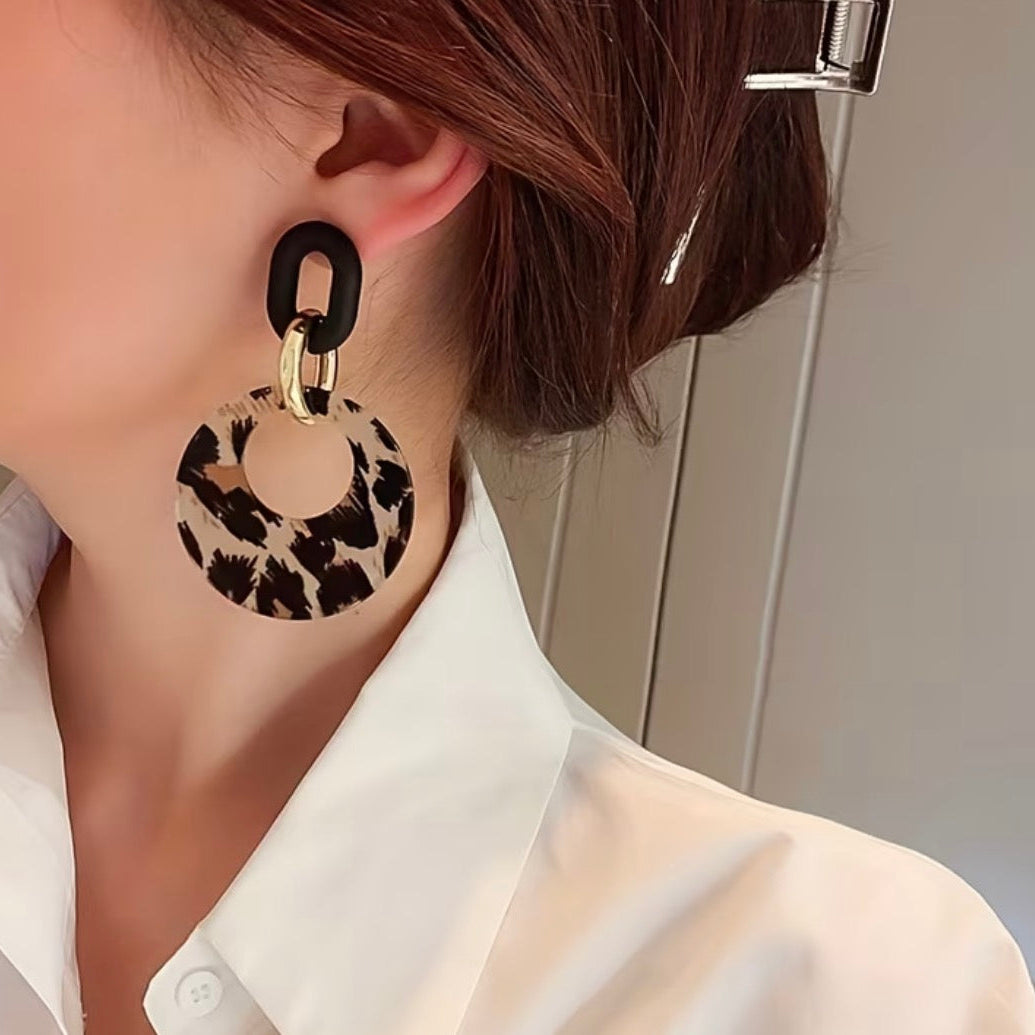 Leopard print earrings worn by a person with a blurred background