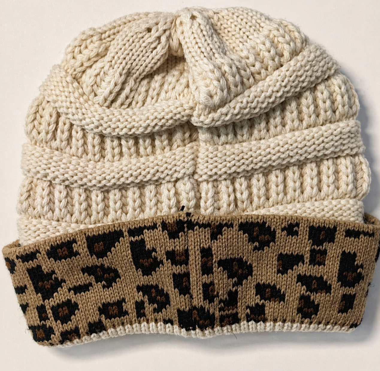 Knitted beanie with leopard print band on a light background