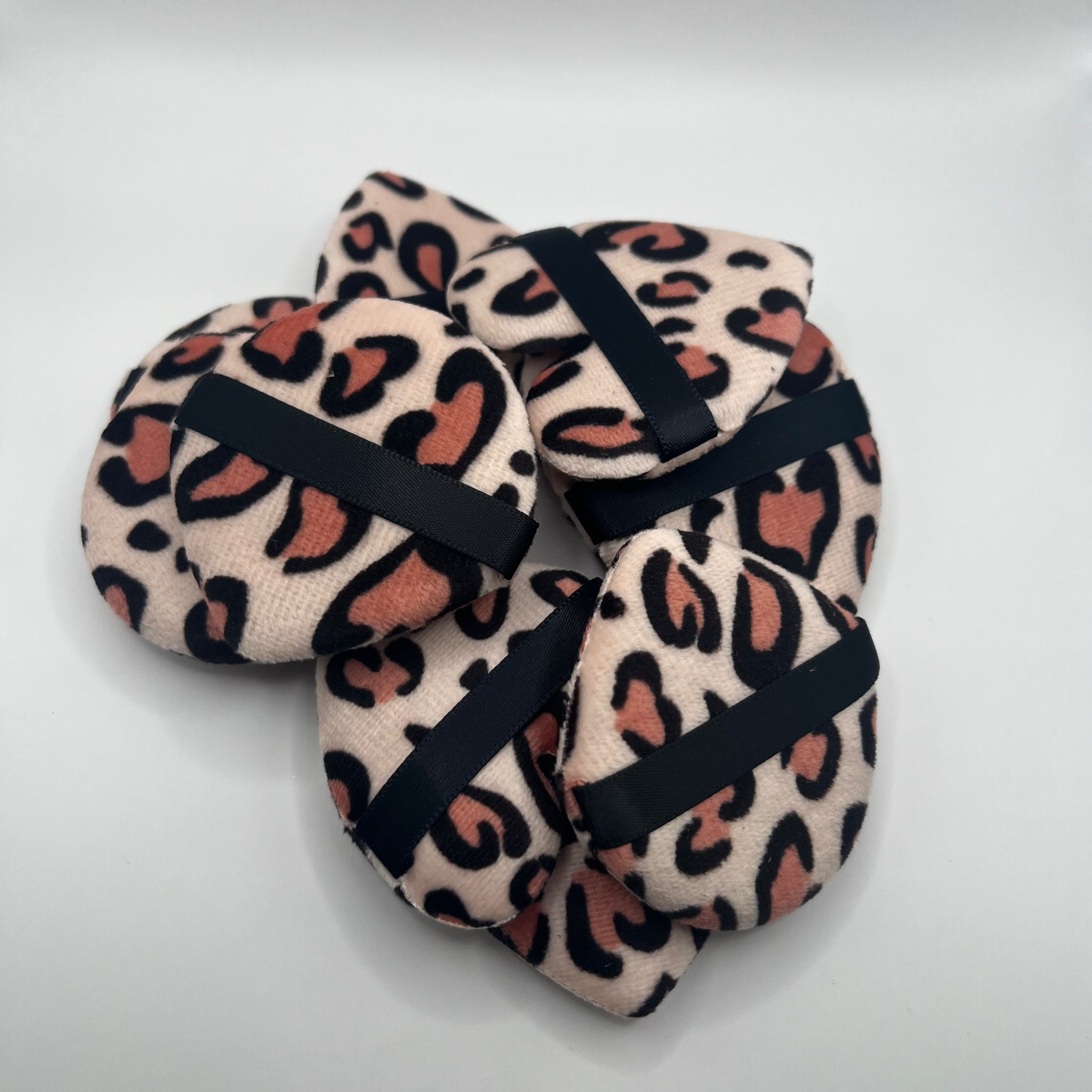 Pair of leopard print sponges with black bands on a gray background