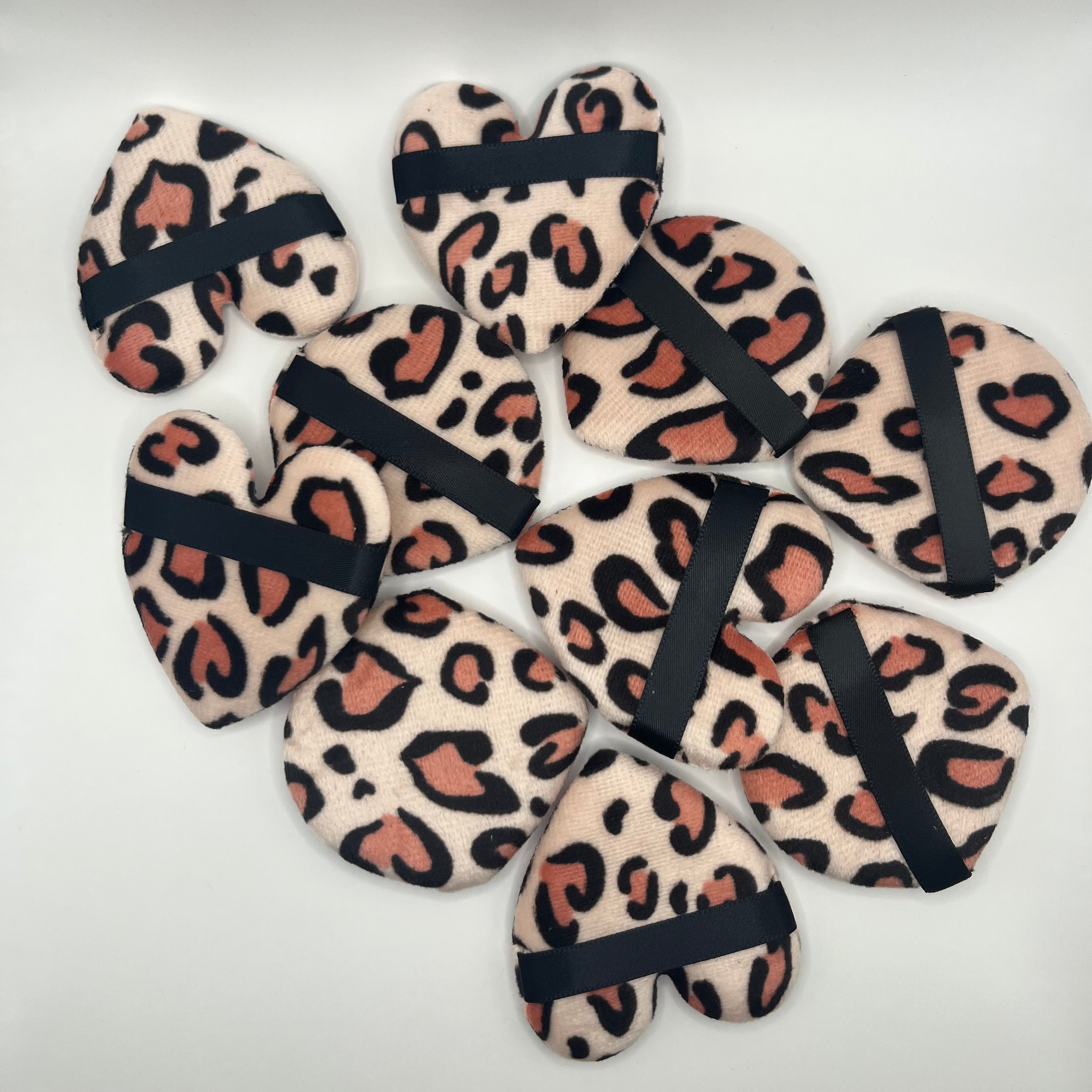 Leopard print face sponges with black bands on a white background
