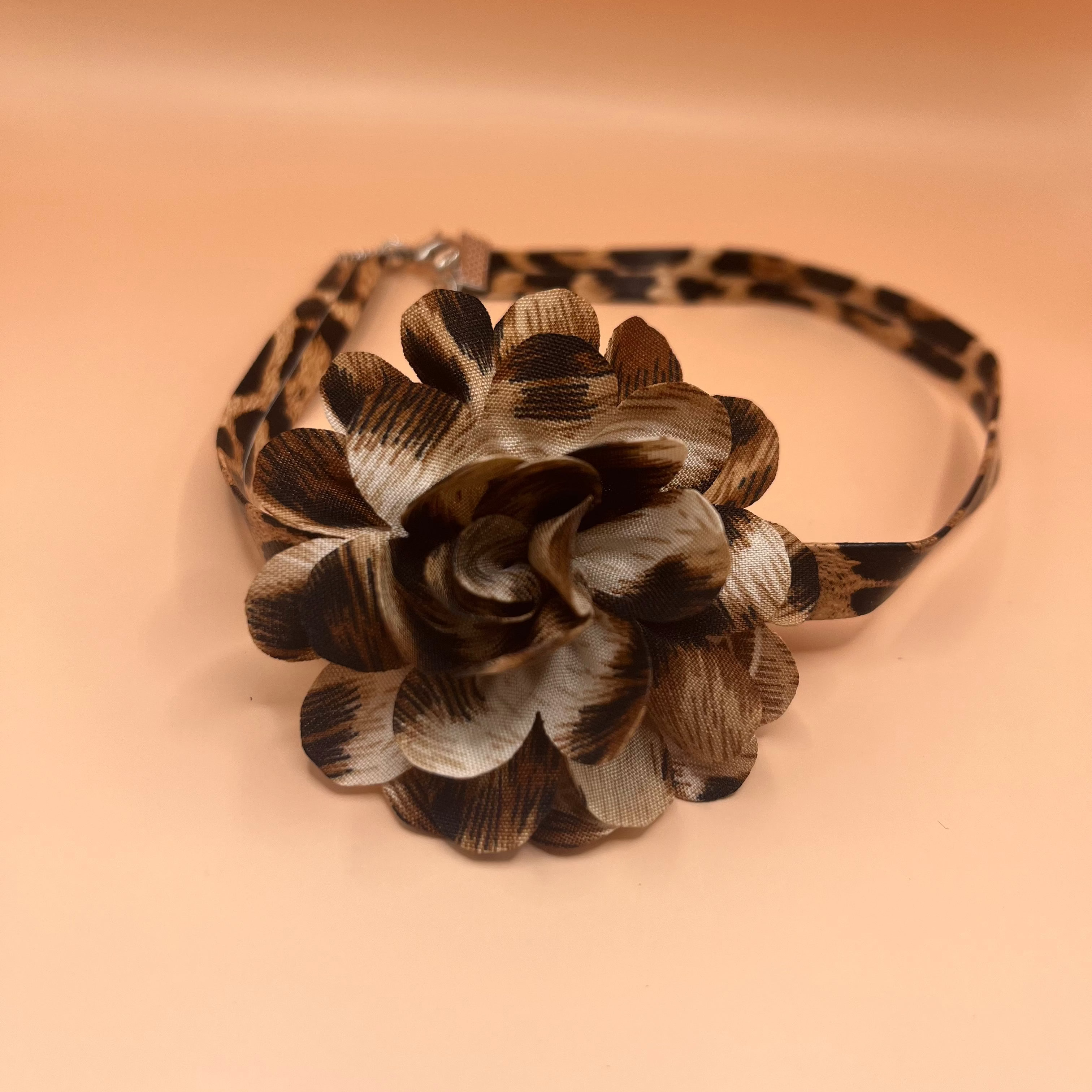 Leopard print choker with a flower-shaped accessory on a beige background