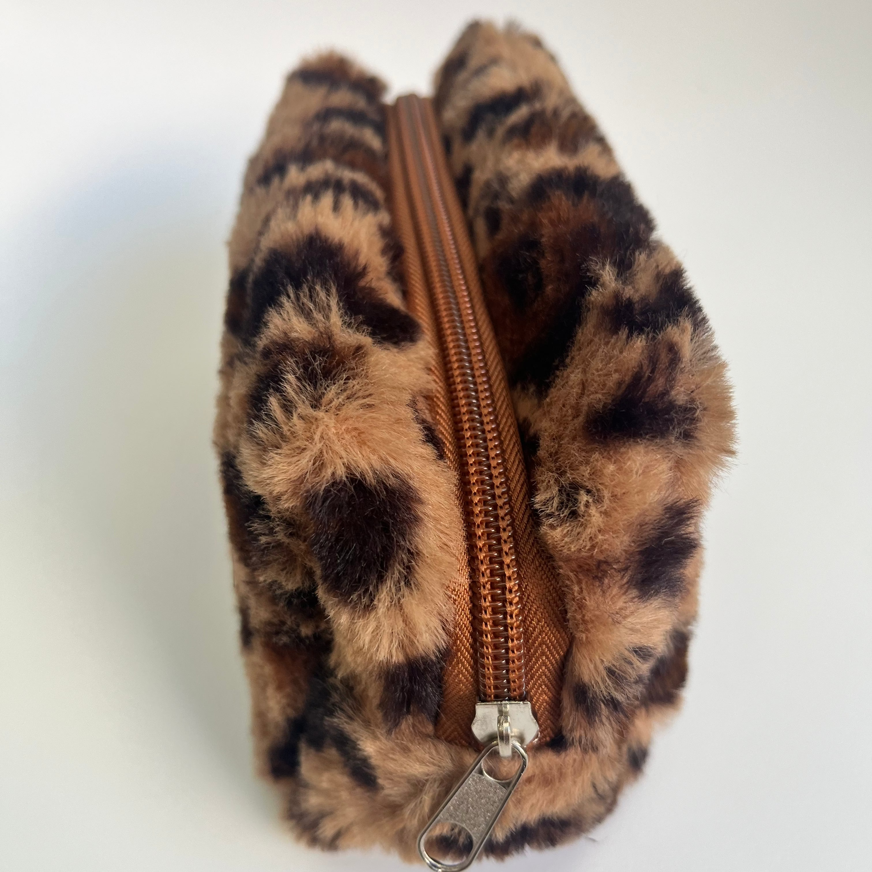 Leopard print pouch with a brown zipper on a white background