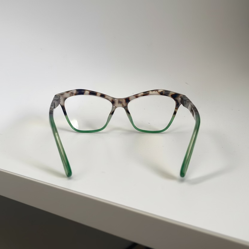 Cat-eye glasses with leopard print and green frame on a white surface