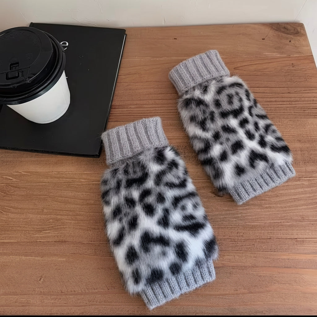 Leopard print arm warmers with light gray cuffs on a wooden surface next to a coffee cup and laptop.