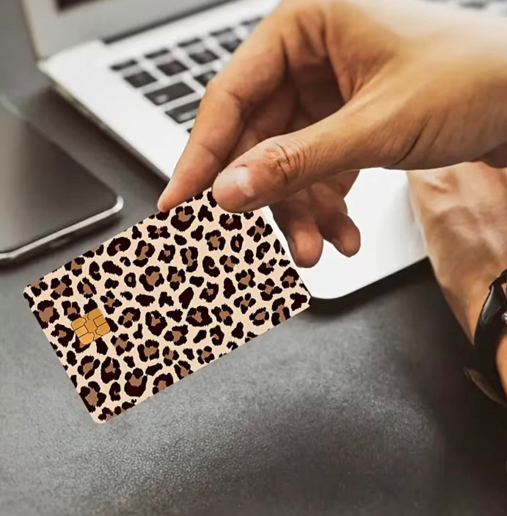 Hand holding a leopard print card with a laptop in the background