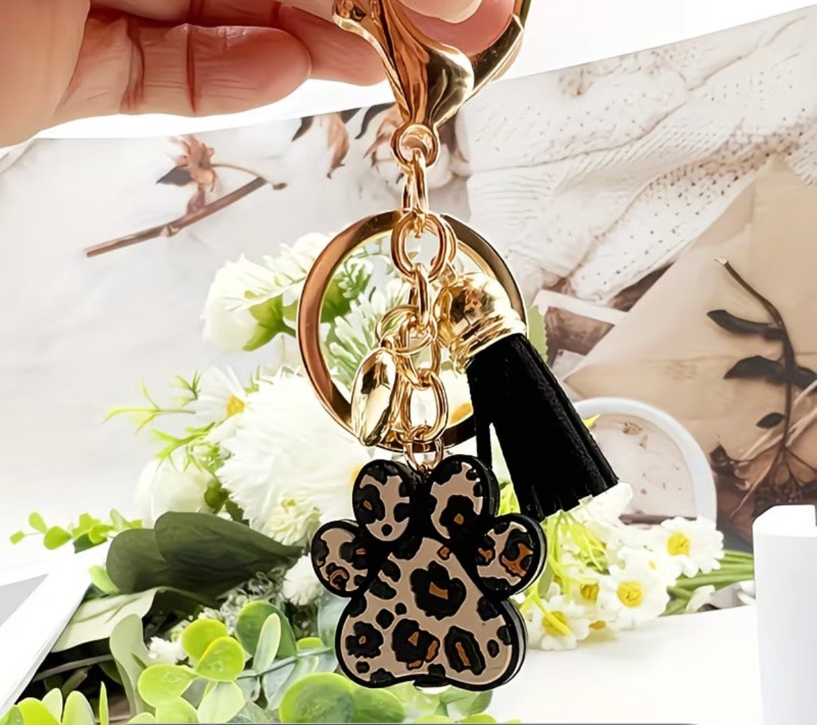 Keychain with leopard print paw charm held over a floral background