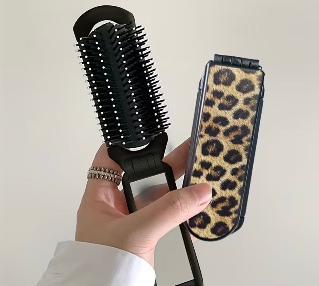 Hairbrush with a leopard print hair brush held by a hand against a neutral background
