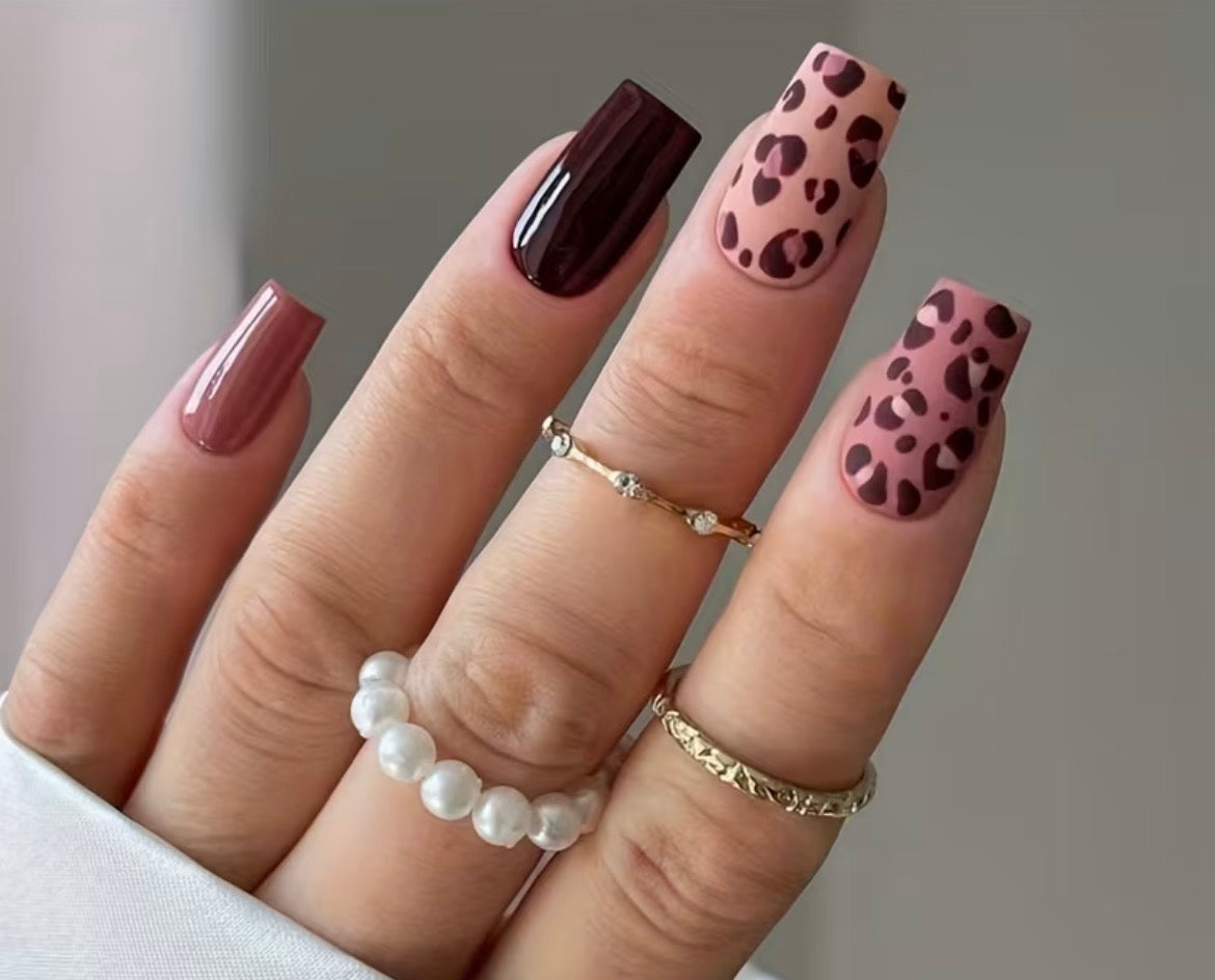 Nails with brown and pink leopard print design on a neutral background