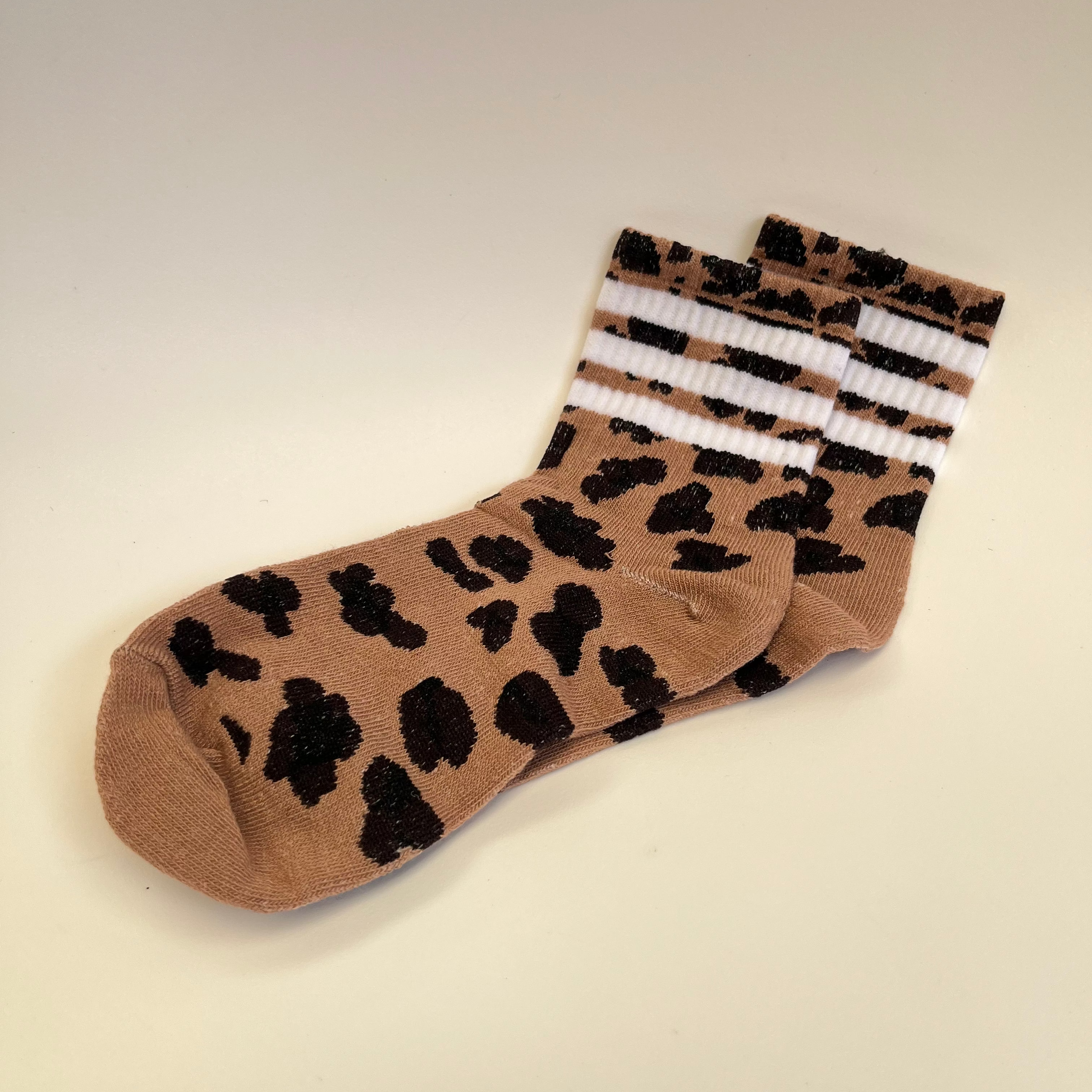 Brown sock with black leopard print pattern on a beige background