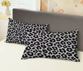 Two leopard print pillows on a bed with a neutral headboard.