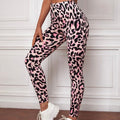 Person wearing pink leopard print leggings with white sneakers in a room with white paneled walls.