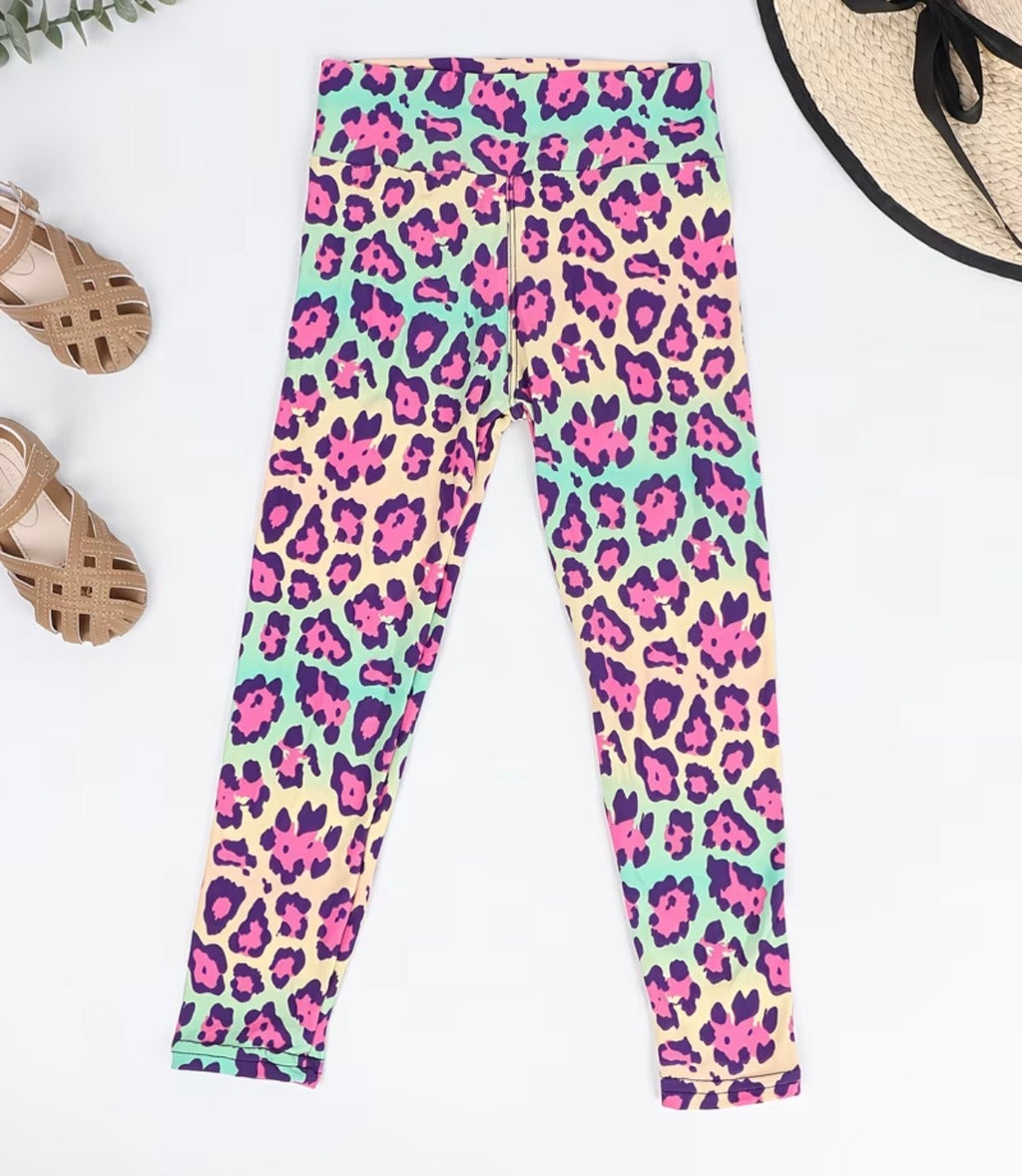 Colorful leopard print leggings on a white background with sandals and a hat.