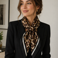 Woman wearing a leopard print scarf with a black blazer indoors.