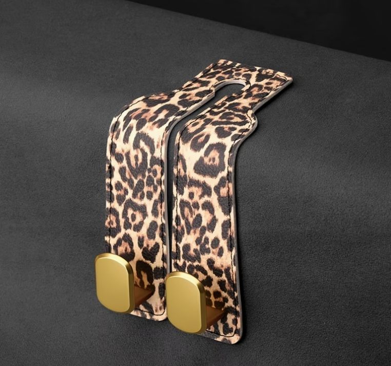 Leopard print car hooks with gold ends on a black background