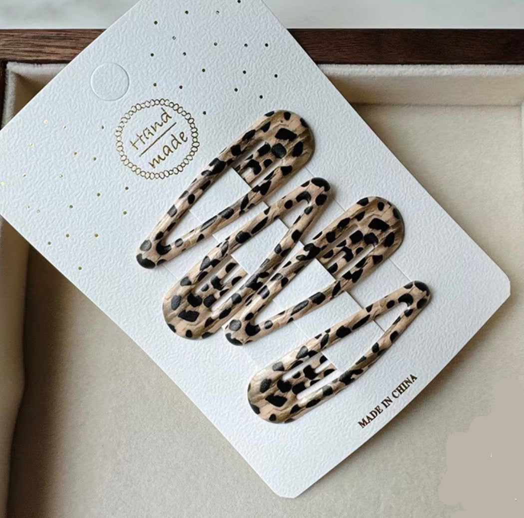 Set of leopard print hair clips on a white card with 'Made in China' text, displayed on a neutral background.