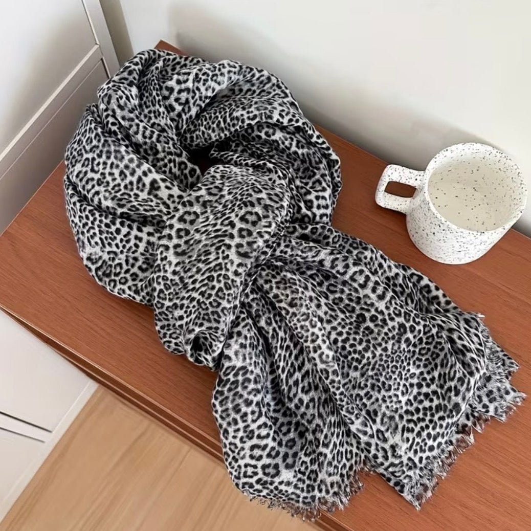 Leopard print scarf on a wooden surface with a white mug.