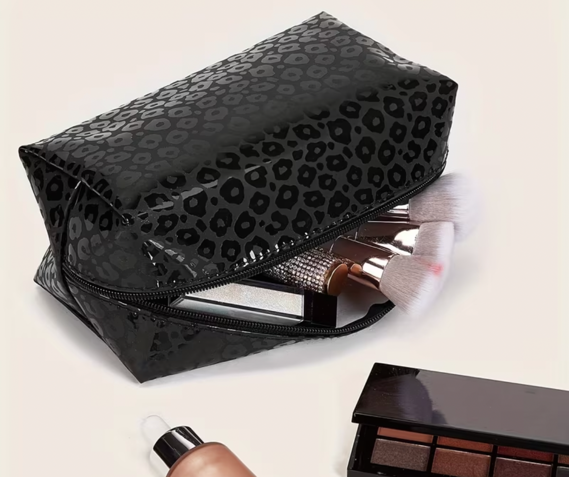 Black leopard print bag with makeup items on a white background