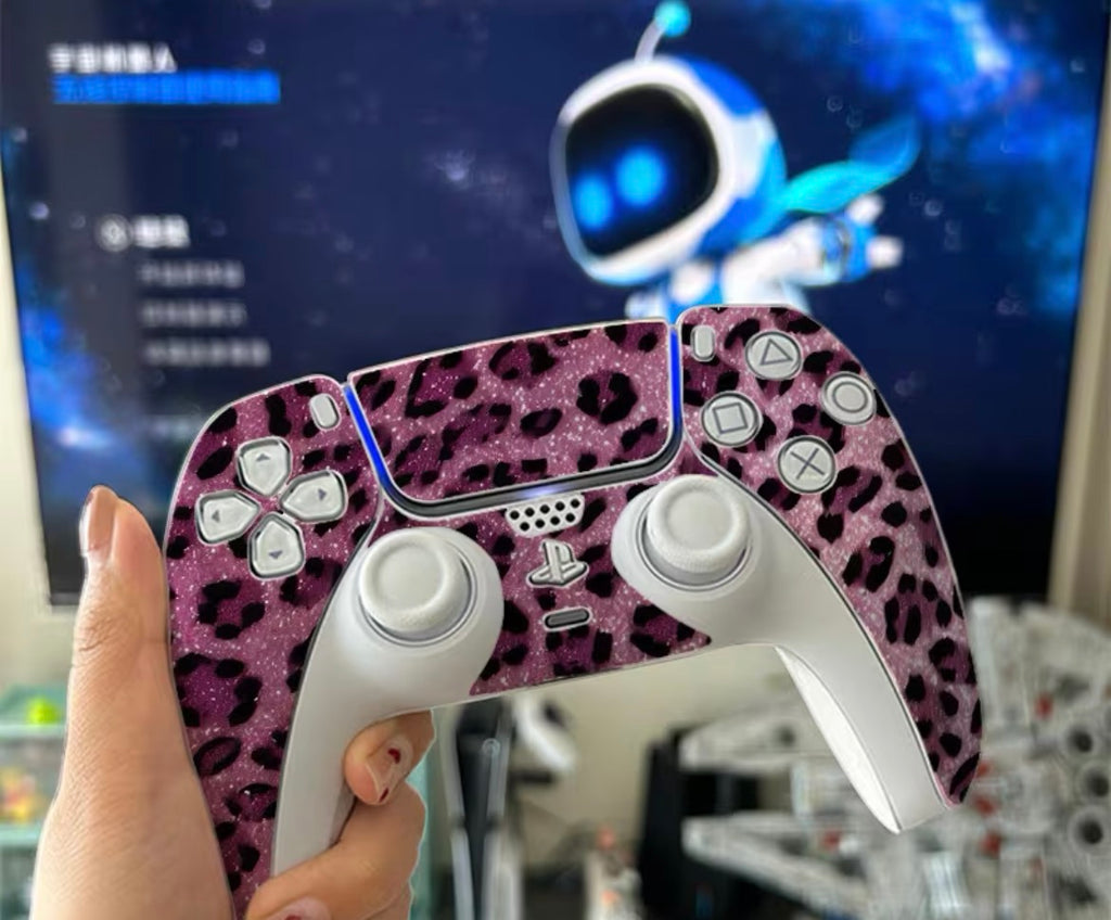Pink leopard print gaming controller held in front of a computer screen with a space-themed wallpaper.