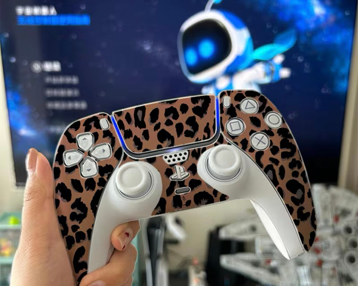 Leopard print gaming controller held by a person with a blurred background of a gaming setup.