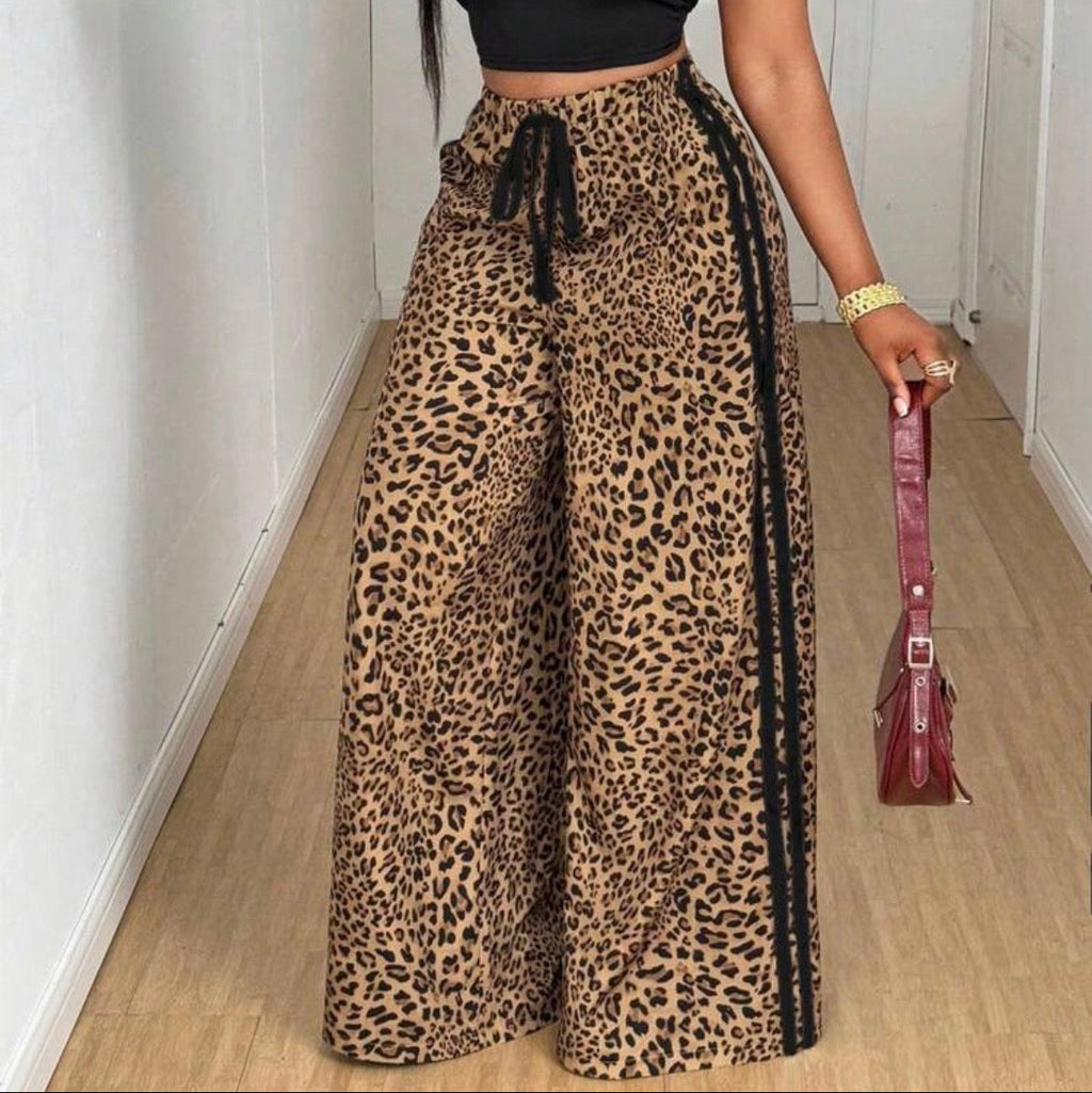 Person wearing a black crop top and leopard print pants, holding a red handbag.