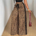 Person wearing a black crop top and leopard print pants, holding a red handbag.