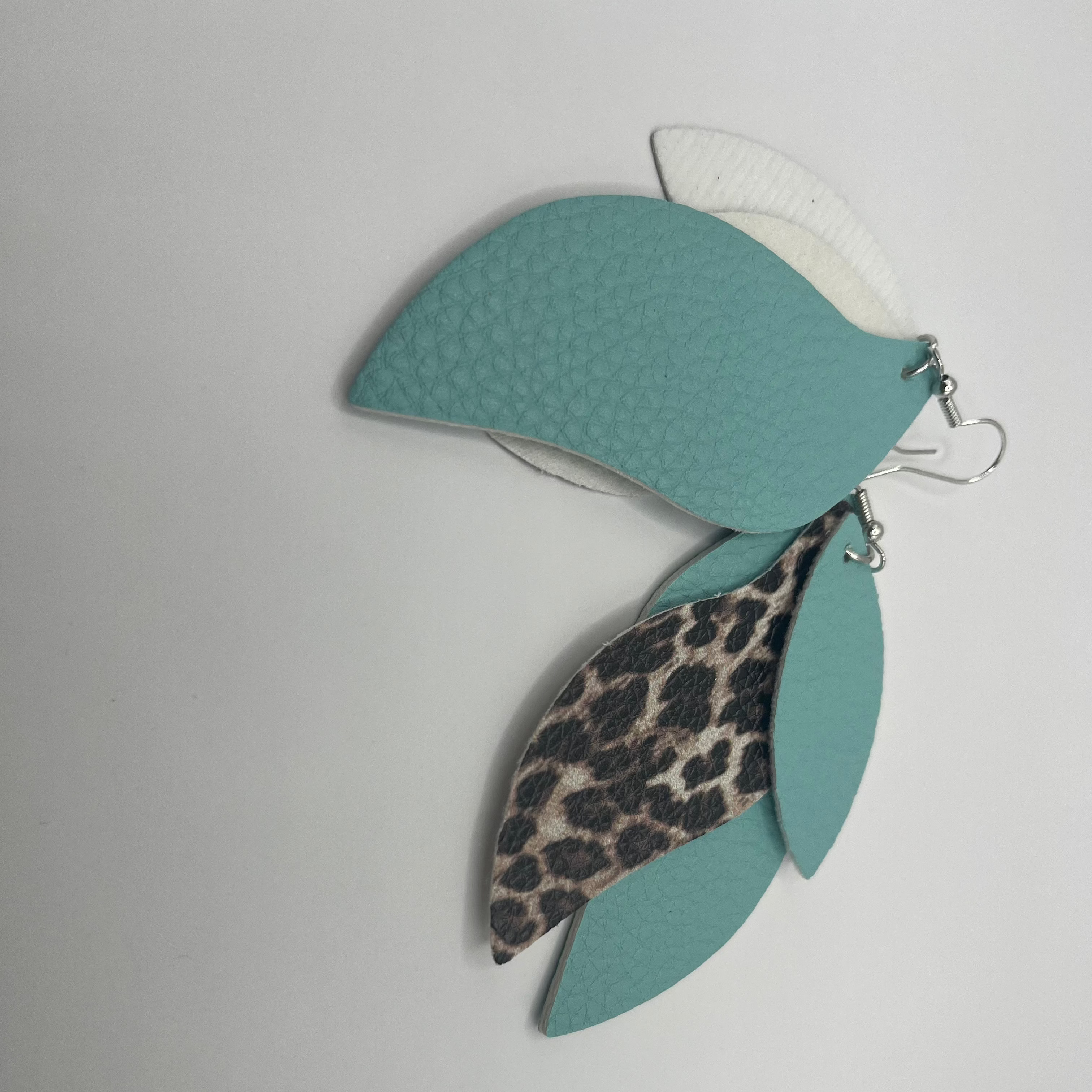 Teal and leopard print earrings on a light gray background